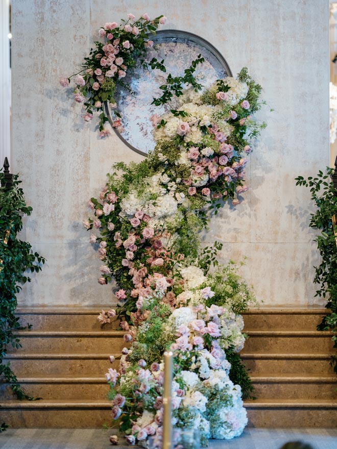 A white pink and green floral arrangement going down the stairs. 