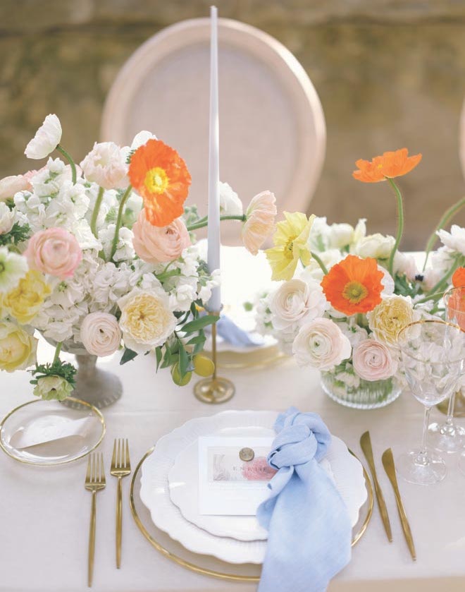 A tablescape with colorful florals and blue candles. 