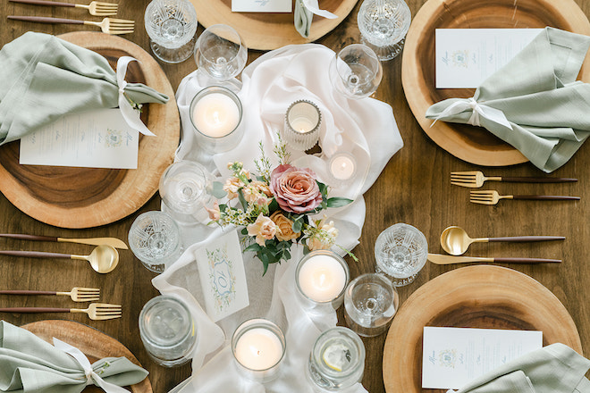 The tablescape decorated with candles, florals and wooden chargers. 