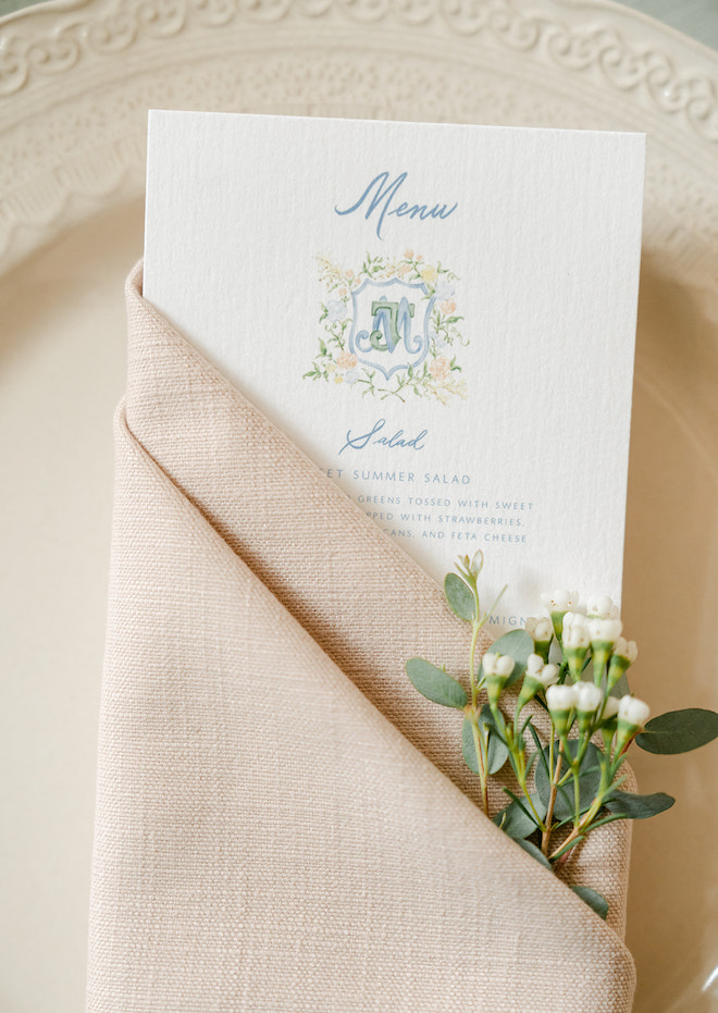 The menu tucked into a pink napkin with small white florals poking out. 