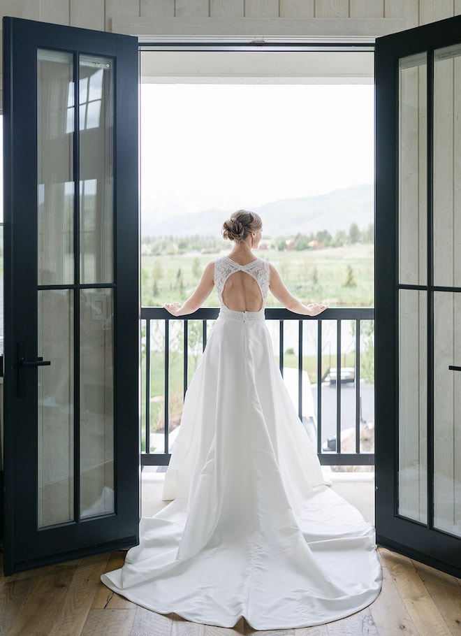 The bride standing over a balcony looking out at the Park City, Utah mountains. 