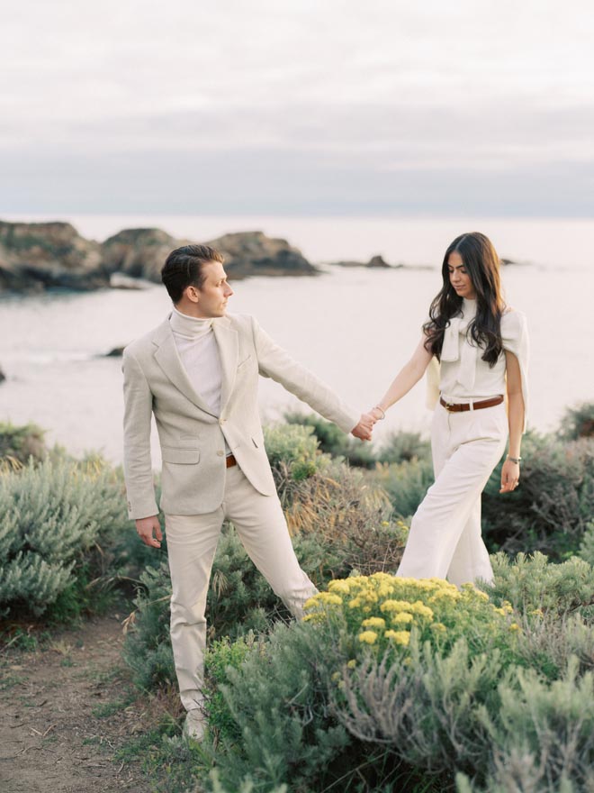 The couple hold hands as the walk along the shoreline of their engagement session by Sean Thomas Photography.