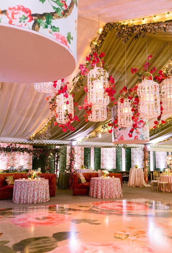 The reception decorated with pink and orange floral print tablecloths, chandeliers and dance floor. 
