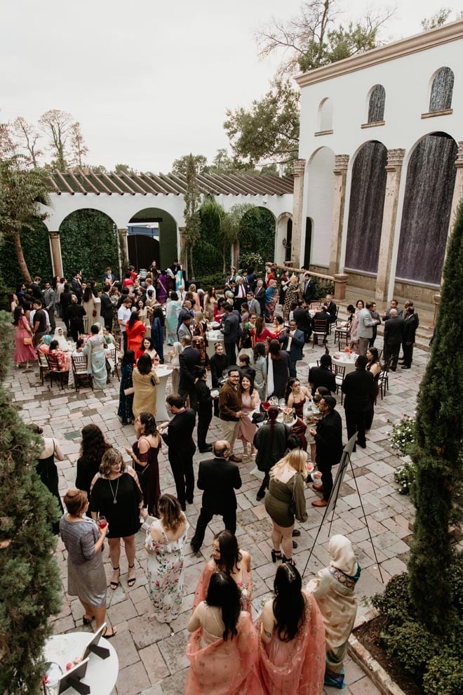 Wedding guests enjoy a cocktail hour in the venue's courtyard near the Waterwall. 