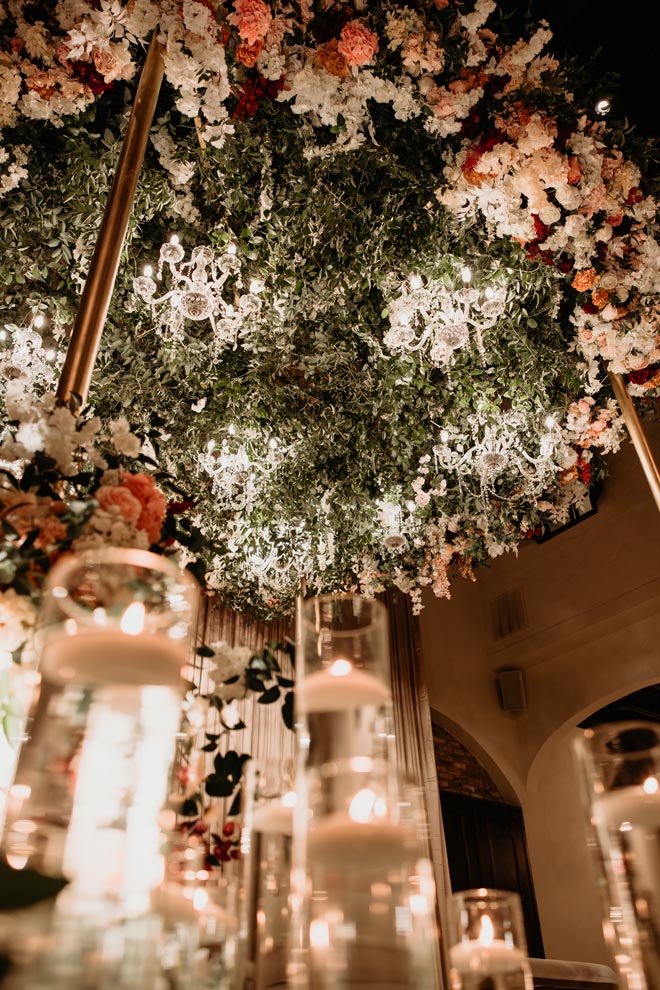 Candlelight and floral instillations of white, blush, peach flwoer and greenery decorate the reception space.