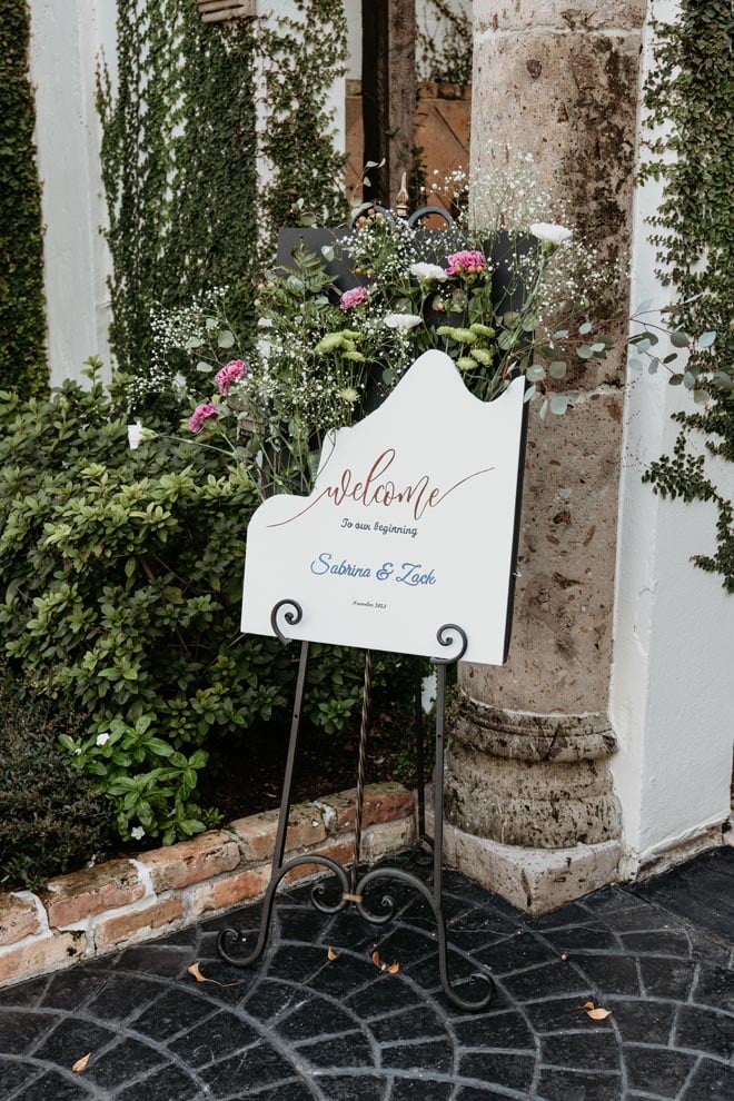 A welcome sign with the bride and groom's name is placed outside the wedding venue. 