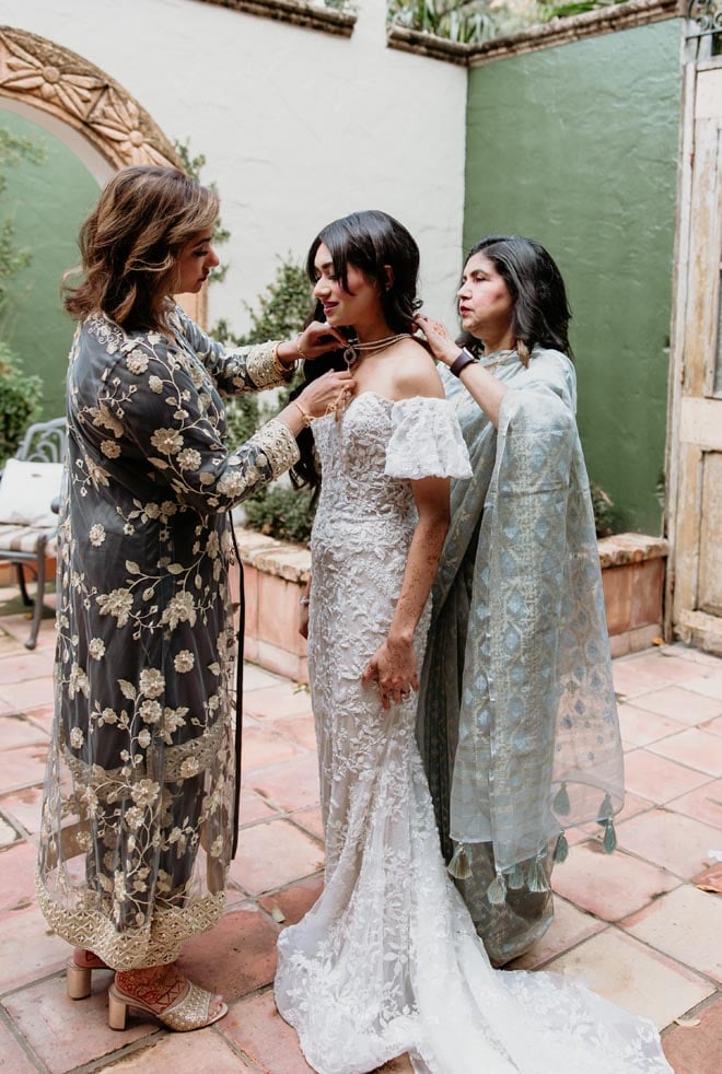 The bride's family help her zip into her wedding gown.