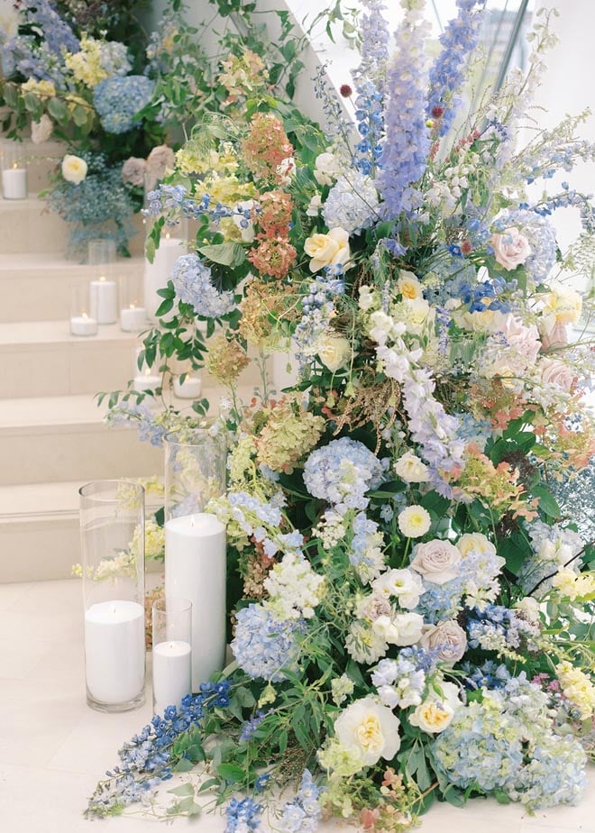 A floral arrangement of blue, white and yellow florals and candles. 