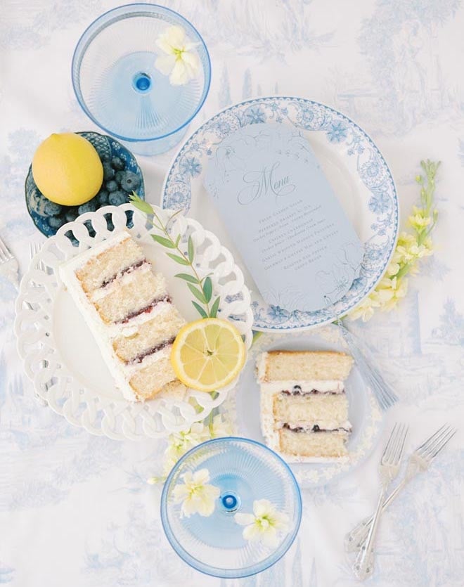 A flat lay with two pieces of cake, a blue menu and blue and white plates.