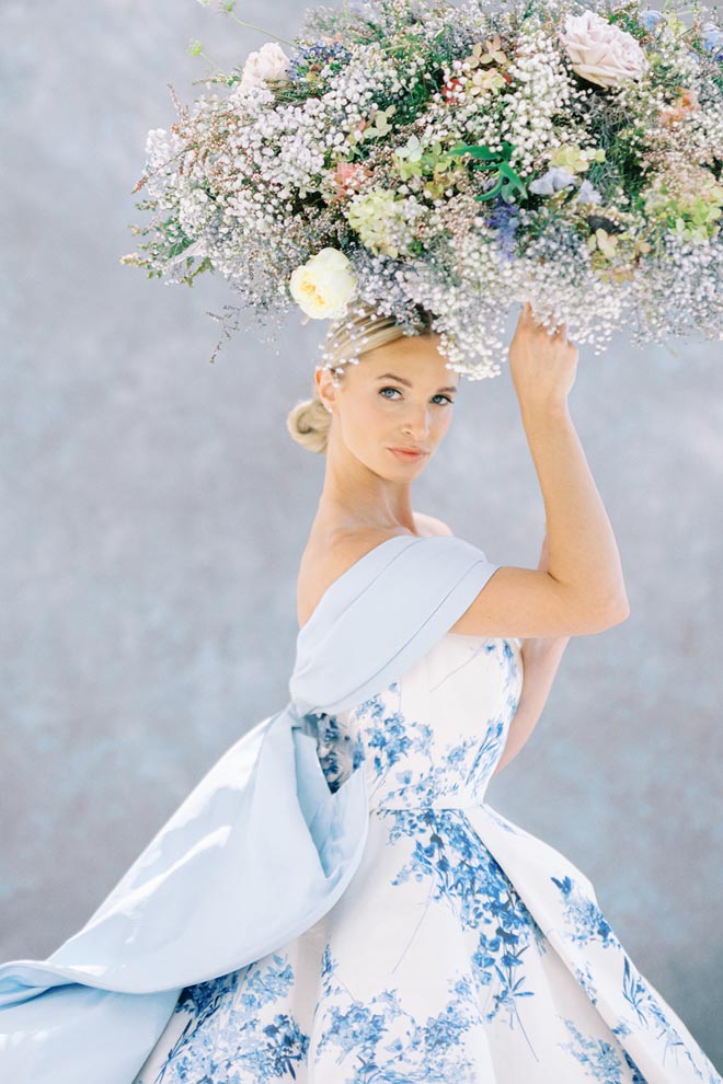 The bride wearing "Hydrangea" by Sareh Nouri and holding an umbrella made of flowers. 