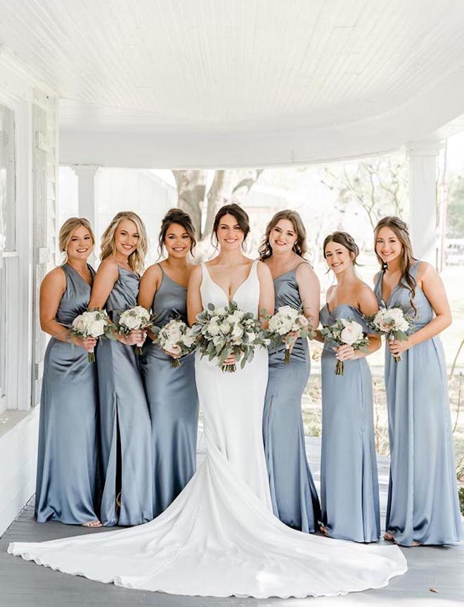 The bride and her bridesmaids stand under a wrap-around porch at a wedding venue in Houston. 