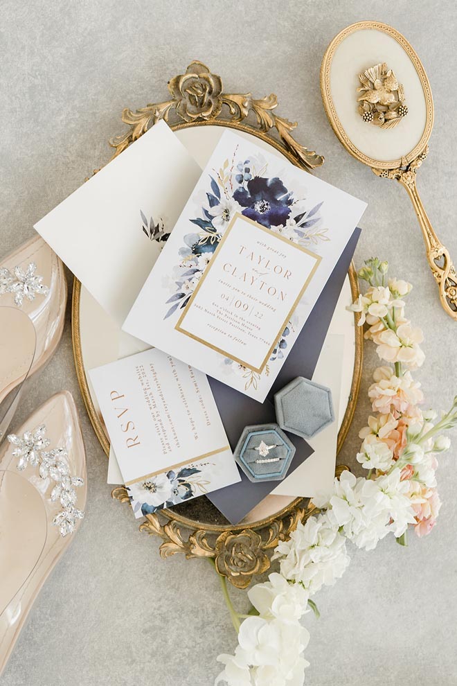 A flat lay of the wedding stationery surrounded by the brides shoes, white and pastel flowers and antique accessories. 