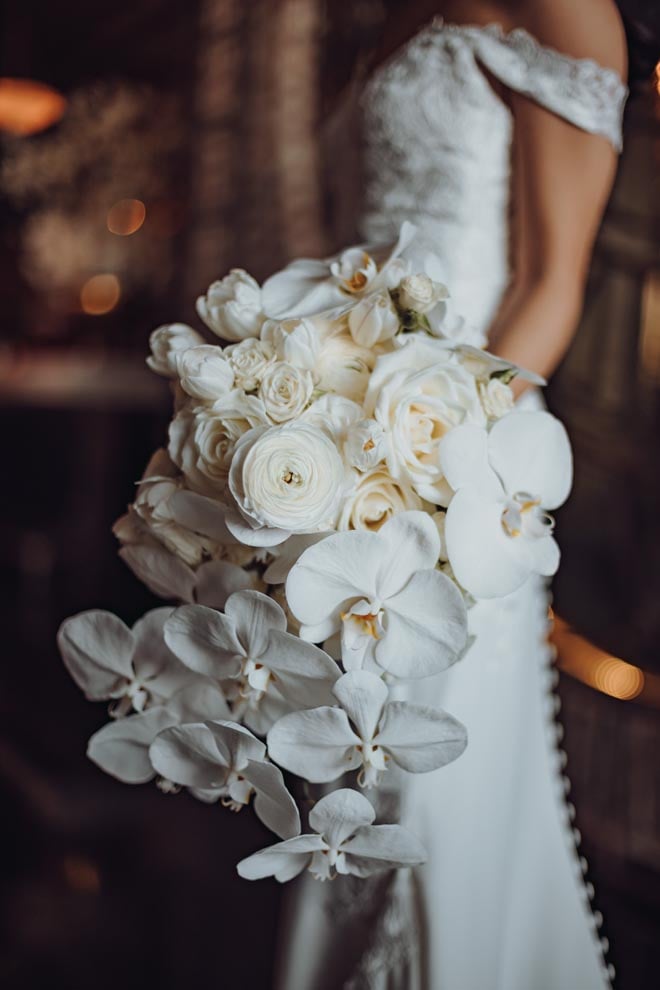 The white wedding bouquet is detailed in orchids, white roses and tulips.