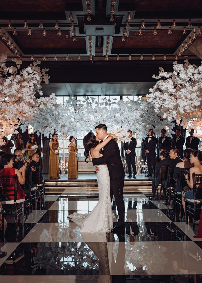 The bride and groom share a kiss in the aisle as newlyweds. 