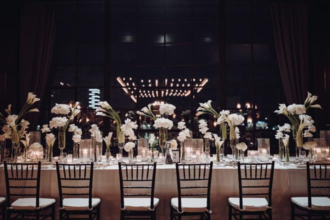 Various white flowers in glass vases detail the reception tables at the Downtown Houston wedding venue.