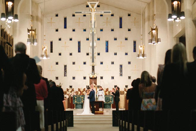 The bride and groom share a kiss at the alter during their church ceremony.