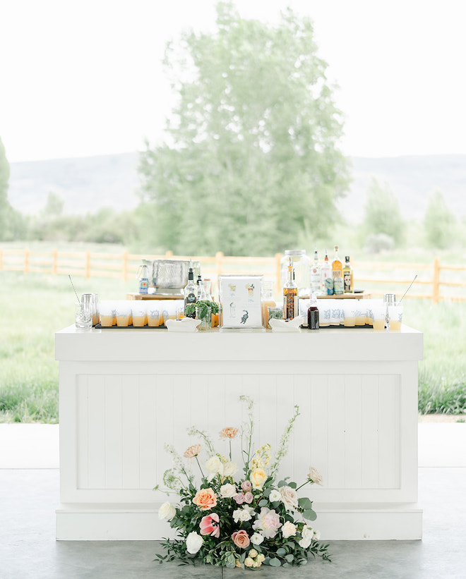 A white bar with a floral arrangement in front of it with the scenic mountains of Park City, Utah behind it. 