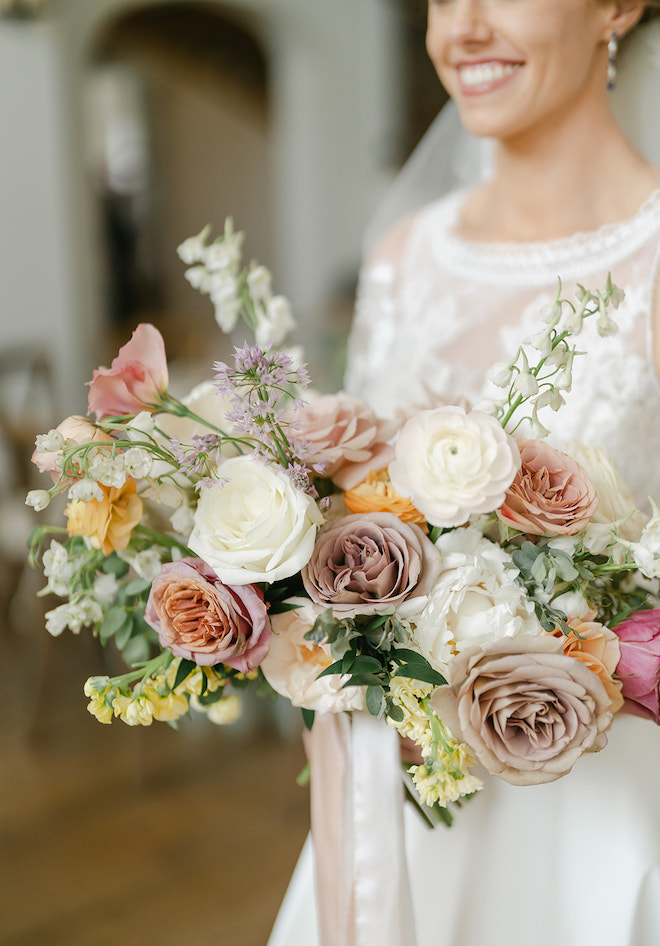 The bride holding a bouquet of white, pink and lavender flowers. 