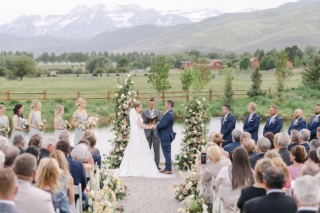 The bride and groom holding hands at the altar with the scenic landscape of Park City, Utah behind them. 
