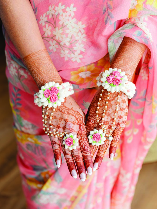 The bride wears pastel jewelry and henna tattoos for her Haldi ceremony. 