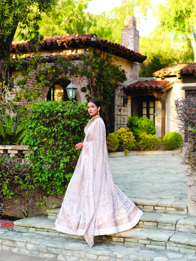 The bride poses in traditional Indian wedding attire outside of her wedding reception in Malibu.