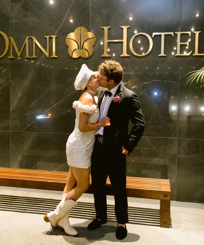 The bride and groom kissing in front on the Omni Houston Hotel. 