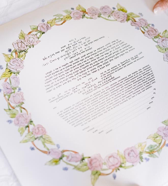 A Ketubah with pink florals circling it. 