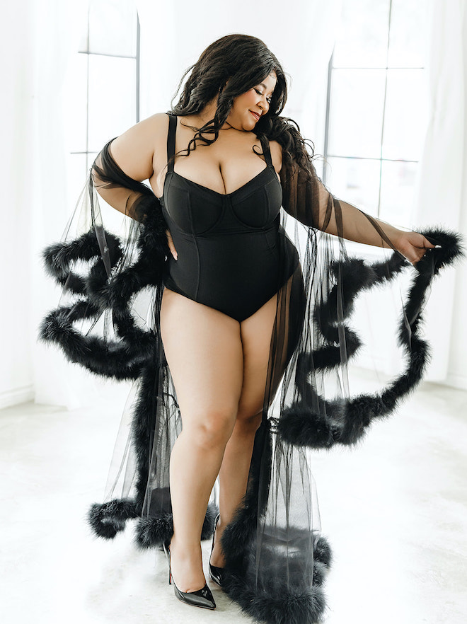 The model wears black lingerie and a sheer robe lined with feathers.