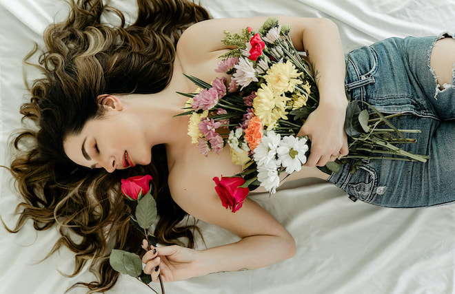 The model uses her wedding bouquet to cover her chest for her boudoir session. 