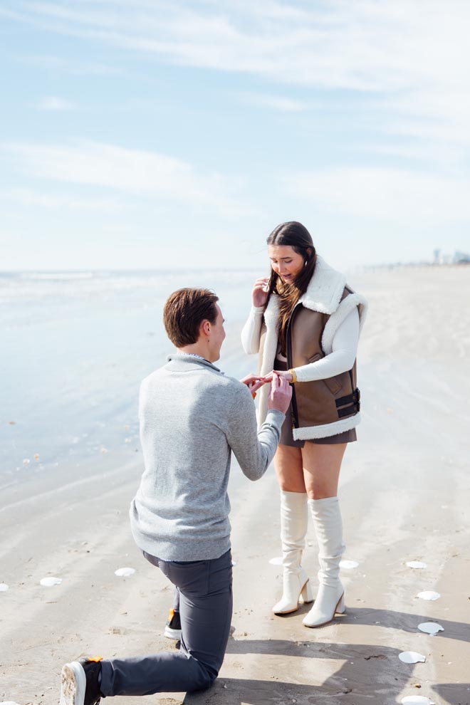 The boyfriend gets down on one knee and asks his girlfriend to marry him on the beach in Galveston.