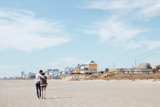 The couple walk along the beach embracing one another after their dream proposal in Galveston. 