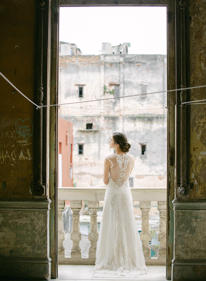 A bride standing on a balcony overlooking the streets of Havana.