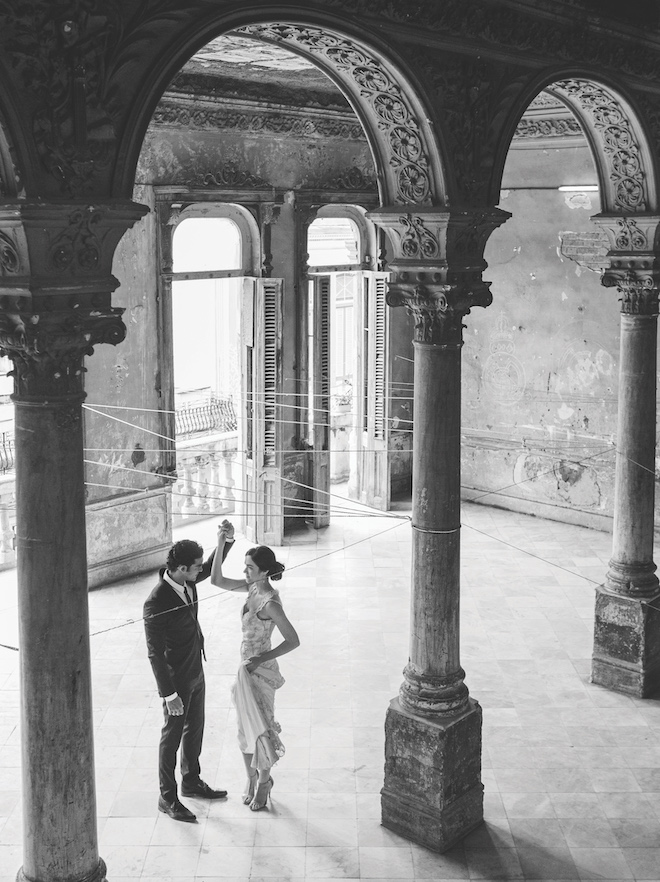 A bride and groom dancing in a building with ornate columns.