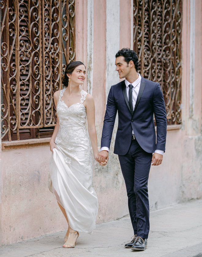 The bride and groom walking the streets of Havana holding hands. 