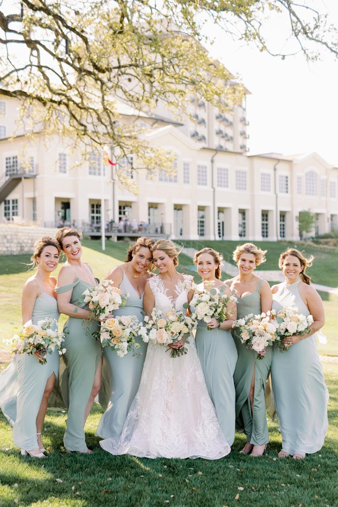 The bride and her bridal party stand outside the Texas hill country wedding venue, Omni Barton Creek Resort & Spa.