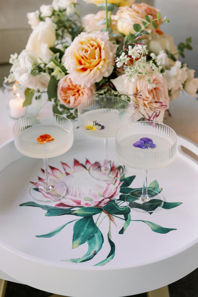 Coupe glasses with vibrant florals are served to wedding guests. 
