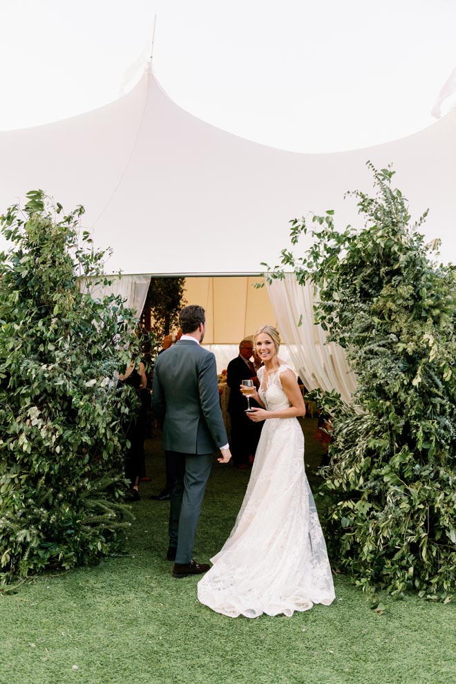 The bride and groom walk into their tented wedding reception in the Texas hill country.