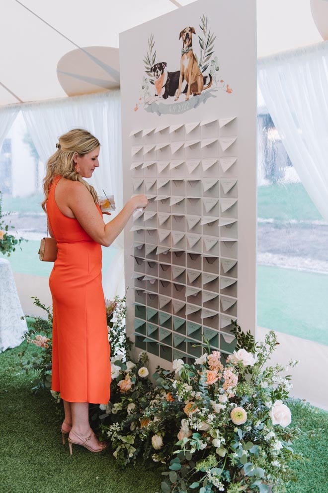 A wedding guests finds her seat on the seating chart at the outdoor wedding reception. 
