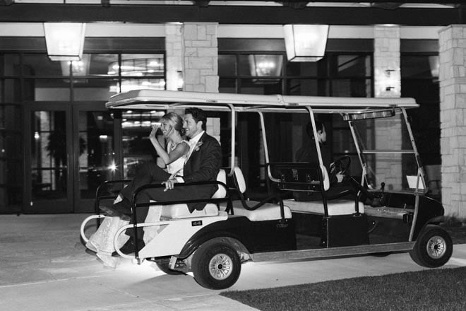 The bride and groom ride off from their wedding reception on a golf cart. 