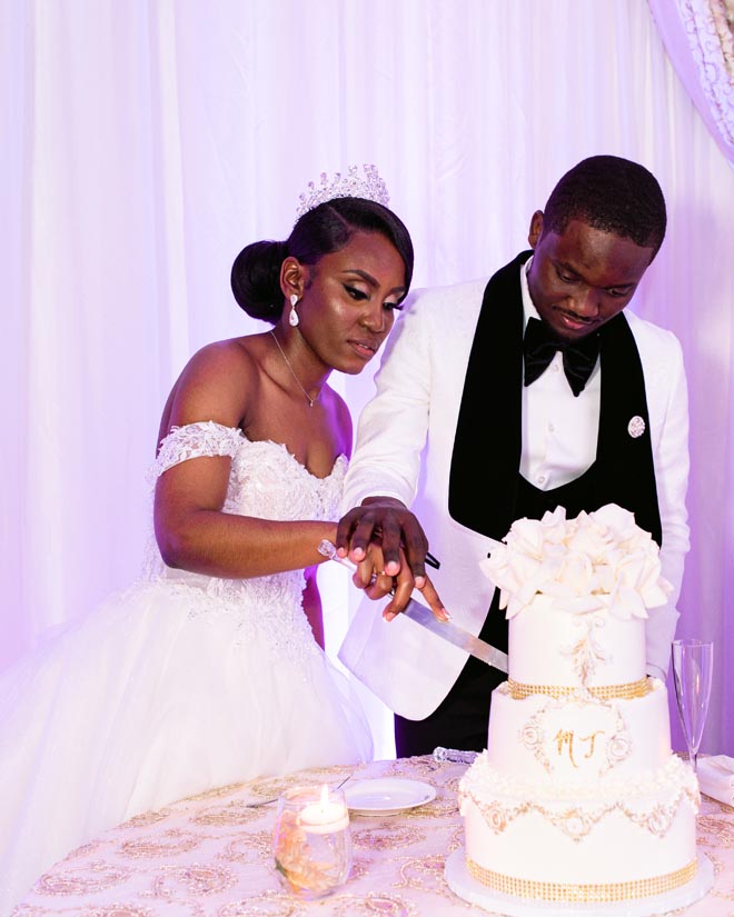 The bride and groom slice into their wedding cake at their intimate ballroom wedding.