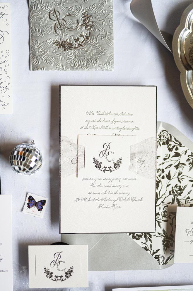 White and gold wedding stationery lay on a white surface. 