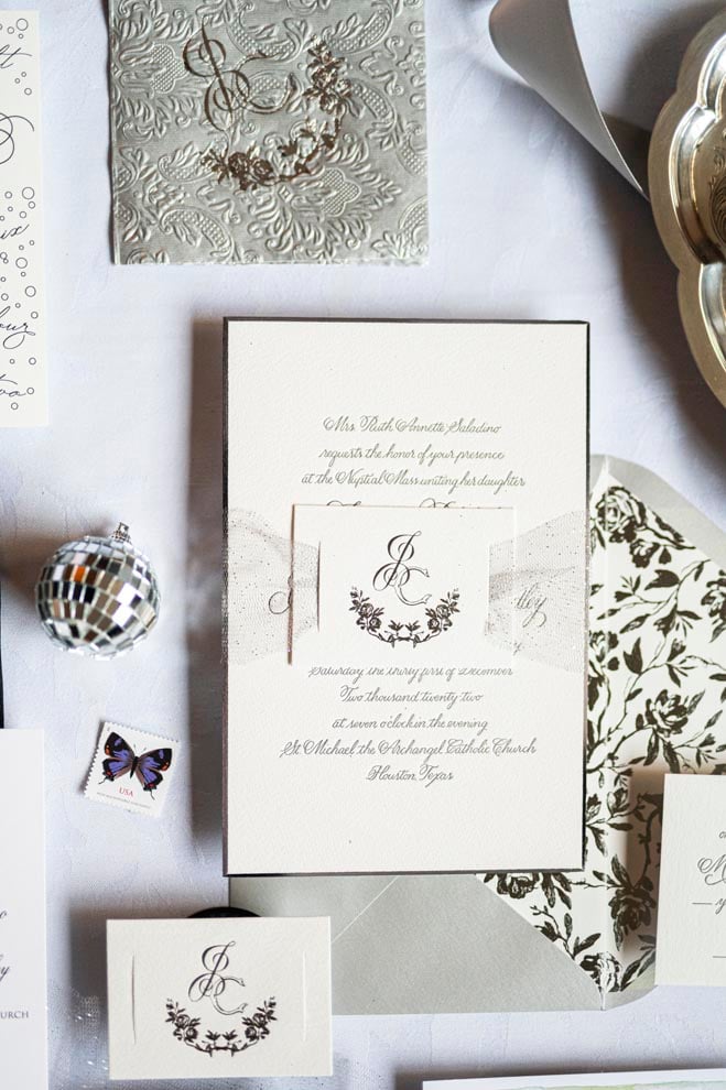 White and gold wedding stationery lay on a white surface. 