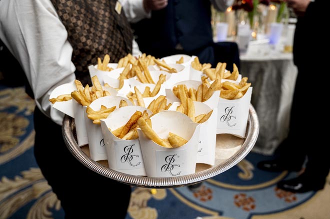 Late night snacks held in a white container with the bride and groom's initials are passed out at the reception. 