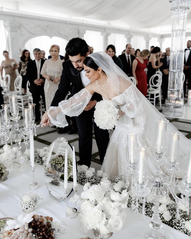 The bride and groom light a candle on the Sofreh for their Persian wedding.