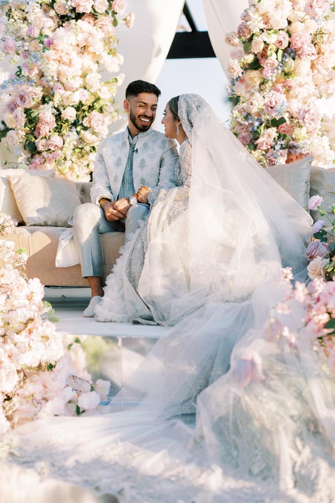 The bride and groom are surrounded by pastel florals at the altar. 