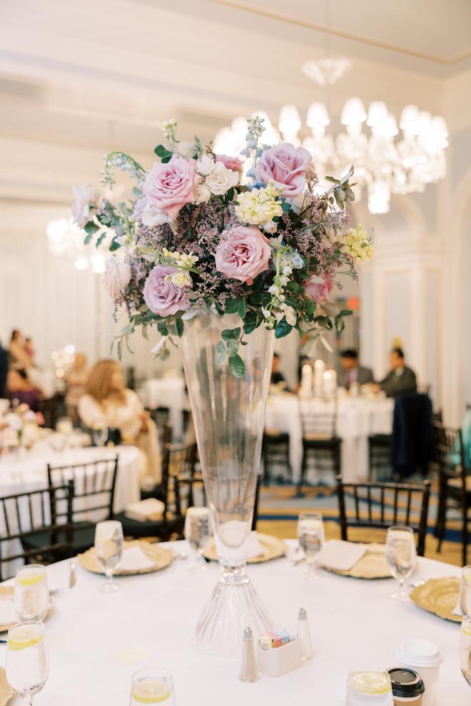 Floral centerpieces of lavender roses and greenery decorate the reception tables in the ballroom at the Grand Galvez.