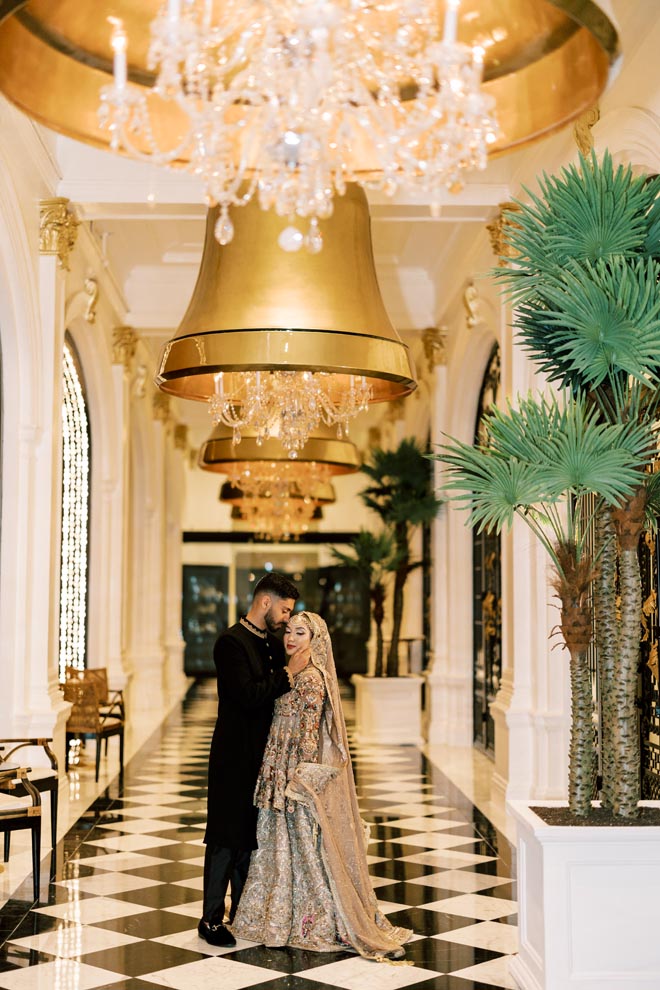 The bride and groom stand in the atrium of the historic Galveston hotel, the Grand Galvez. 