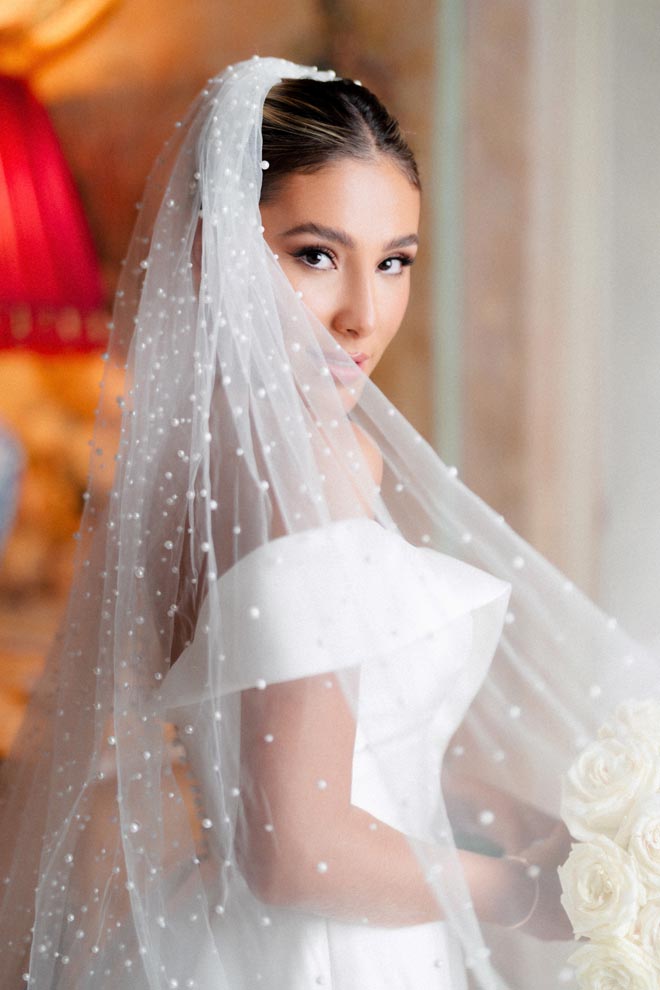 Wedding photographer, Bottega53 captures a photo of the bride overlooking her shoulder wearing her wedding veil. 