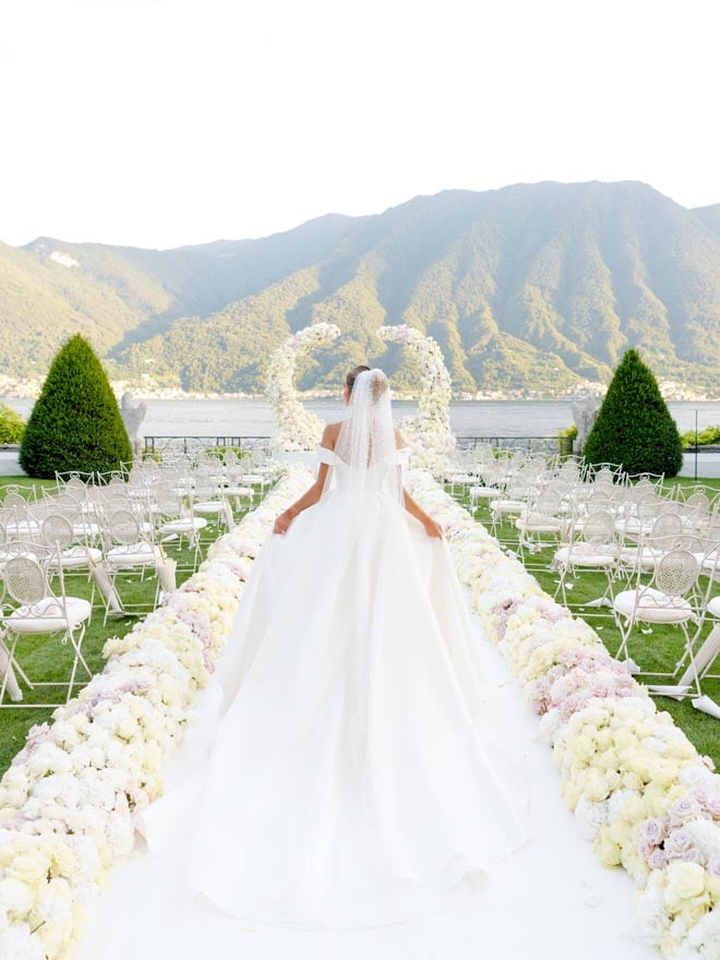 The bride walks down the aisle in a Nicole Milano wedding dress for her Lake Como wedding.