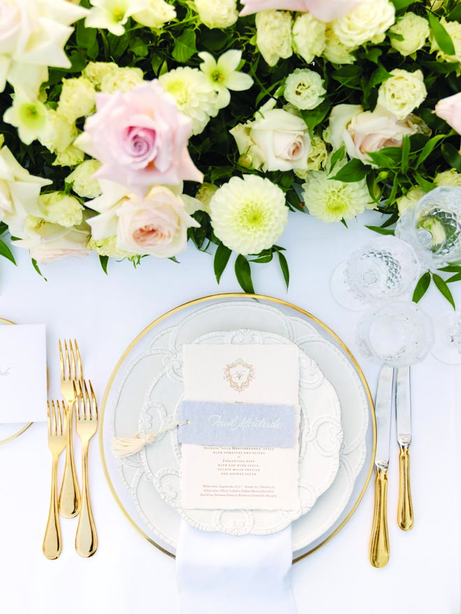 Gold silverware, chargers and white plates detail the wedding reception tables. 